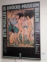 Front view of framed artwork poster titled 'Otto Mueller Im Brücke-Museum Berlin' showing two nude figures, foliage, and exhibit information in German.