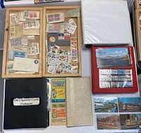 Two wooden trays holding loose postage stamps, a gray Bicentennial cover folder, three binders and saver booklet on table