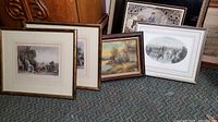 Five framed prints and engravings arranged on carpet with various wood and gold frames