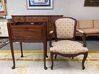 Photo showing vintage wooden drop front side table next to a vintage upholstered wood chair on a yellow patterned rug