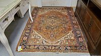 Photo of entire vintage Hariz rug on floor showing central medallion and border patterns with wear and frayed edges.