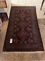 Full view of first rug showing dark background, central medallions and fringed end