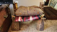 Wooden camel saddle with cushions and saddlebag on top, showing structural details including lacing on legs
