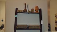 Shelving unit displaying the seven pieces included in the lot: four wooden inlay boxes of various sizes and shapes, a brass and wood vessel, a small inlay container, and the orange Denver Broncos wooden football.