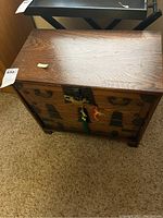 Full view of wooden chest showing metal handles and lock with attached key tassel.