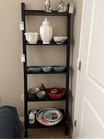 Front view of the black wooden 5-shelf ladder shelf with various decorative ceramic items on shelves.