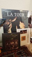 Photo showing large Georges de La Tour Muse du Louvre poster with smaller art prints and Crosby Stills Nash & Young vinyl album in front of it.