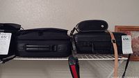 Sony Handycam, binoculars, and Optoma projector cases stored on a shelf