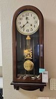 Full view of Santos 31 Day wall clock showing wooden case, dial, and pendulum.
