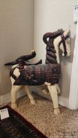 Full side view of vintage wood temple horse showing detailed carvings and bird on saddle.