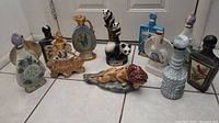Full view of all 12 ceramic decanters arranged on floor showing variety of animal shapes and decorative bottles