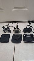 Overview photo showing three binoculars and their cases arranged on a tiled floor.