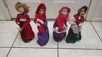 Group photo of 4 Beyers Choice caroler figurines showing full height and clothing details with slight base wear.