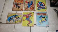 Overview photo showing all six metal comic signs featuring Thor, Superman, Captain America, Batman and Robin, Spider-Man, and Wolverine.