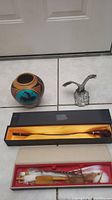 Photo of all four items: signed pot, pewter eagle figurine, talking stick in box, and pipe in box