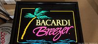 Photo showing the illuminated Bacardi Breezer sign with palm tree and waves.