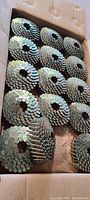 Top view inside an open box showing neatly coiled roofing nails arranged in rows.