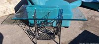 Side view showing the Singer sewing machine base supporting large rectangular glass top outdoors.