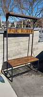 Full front view of the hall tree showing wooden top shelf, hook panel, bench, and bottom rack.