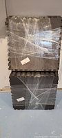 Stacked gray interlocking foam floor mats wrapped in plastic, showing puzzle-like edges for connecting.