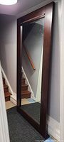 Full view of the large floor mirror positioned near a stairway, showing the size and shape.