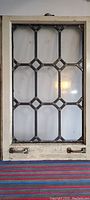 Large leaded glass window with white painted wooden frame showing wear and hardware at bottom