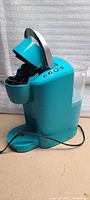 Side angle of teal Keurig coffee maker with water reservoir and control buttons visible