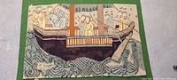 Front view of one hand woven tapestry showing boat with people fishing and aquatic animals in water