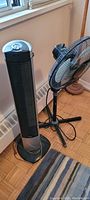 Tower air conditioner and oscillating pedestal fan together showing overall lot condition and size comparison