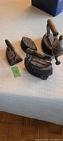 Four antique cast iron decorative irons of varying sizes and styles displayed on white fabric.