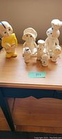 Seven vintage plastic figures from 1970s including Pillsbury Doughboy family and football player on display on wooden surface
