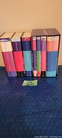 Side view of 7 Harry Potter books arranged vertically showing colorful spines by J.K. Rowling.