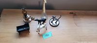 Six miniatures arranged on a wooden surface including Beswick horse, trough, lamp, tree, cat, and dog figurines