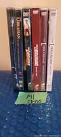 Spine view of 6 DVDs for The Librarians seasons, showing unopened sealed cases with various cover colors and logos.