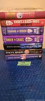Stacked six paperback novels showing spines with titles and authors for identification.