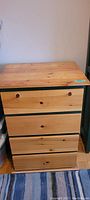 Front view of the dresser showing four drawers with natural pine finish drawer fronts and green painted sides.