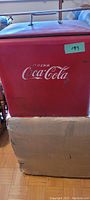 Front of cooler showing red painted exterior and white Drink Coca-Cola logo