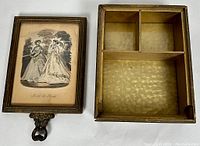 Open decorative box showing divided interior and framed lid with vintage fashion illustration under glass