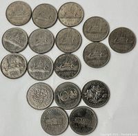Top view of all 17 coins showing obverse and reverse sides including the cohort of voyageur silver dollars and centennial nickels.