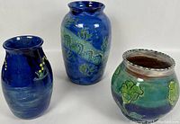 Three Earthworks pottery vases shown together with varied shapes and glaze colors