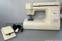 Machine body on table alongside foot pedal and power cord