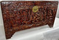 Front view showing full carved relief panel and central brass circular lock plate