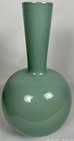 Front view of the vase showing large round base and tall narrow neck with smooth glossy celadon green glaze.
