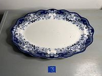 Large oval serving bowl with blue and white floral pattern and scalloped edges on gray surface with number 3 card.