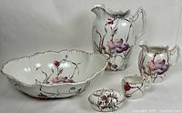 Full set of Victorian wash jug, bowl, small pitchers, and soap dish showing hand-painted floral motif and gilt trim.