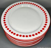 Stack of eight vintage white dinner plates with red polka dot rims photographed from slightly above.
