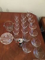 Full set of crystal stemware glasses arranged on table with covered candy dish and can for scale