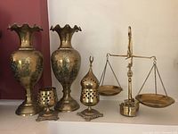 Full view of all brass items including vases, brass scale with pans, decorative holders, and weights