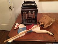 Vintage-style metal birdcage, painted wooden hobby horse, burlap wall hanging, and Russian nesting doll in lot