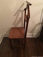 Side view showing the wooden frame and woven seat of the folding clothing butler.